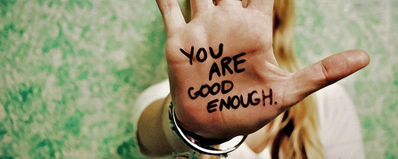 Hand with words you are good enough written on it